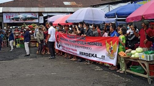 Sejumlah pedagang di Pasar Baturiti membentangkan spanduk selamat datang yang disertai tulisan “Jokowi Bukan Firaun”. Spanduk itu dibentangkan sesaat sebelum Jokowi tiba di Pasar Baturiti, Rabu (2/2/2023).