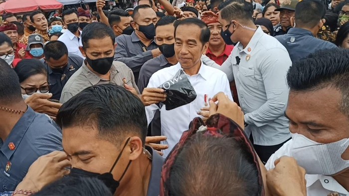 Presiden Jokowi membagikan kaos kepada warga yang berkerumun di depan Pasar Baturiti, Rabu (2/2/2023). (Chairul Amri Simabur/detikBali)