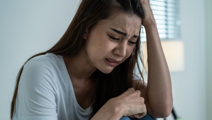 Asian beautiful depression girl crying in tears sit on bed in bedroom. Attractive unhappy young woman feeling sad lonely and upset with life problem and hold tissue on hands in dark night room at home