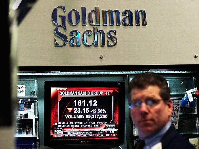 NEW YORK - APRIL 16:  A financial professional works in the Goldman Sachs booth on the floor of the New York Stock Exchange while a television reports airs about the companys lowered stock price April 16, 2010 in New York, New York.  Goldman Sachs was charged with fraud by the Securities and Exchange Commission over its marketing of a subprime mortgage product, sending its stock price sharply lower.  (Photo by Chris Hondros/Getty Images)