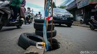 Petugas menutup jalan yang amblas tersebut dengan ban dan bambu.   