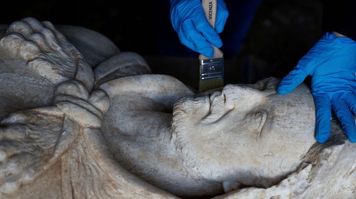 Begini Bentuk Patung Hercules yang Ditemukan di Saluran Pembuangan The feet belonging to a life-sized statue of a Roman emperor posing as the classical hero Hercules lie on a wooden pallet after they were discovered during sewer repair works near the old Appian Way, ancient Rome's first highway, in Rome, Italy, February 1, 2023. REUTERS/Guglielmo Mangiapane