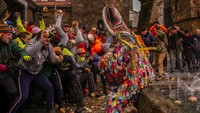 Orang-orang melempar lobak ke arah Jarramplas saat dia berjalan di jalanan sambil menabuh genderangnya selama festival Jarramplas di kota kecil Piornal, Spanyol barat daya, Spanyol, Jumat (20/1/2023). Festival Jarramplas menampilkan seorang pria dengan pakaian warna-warni dan tutup kepala kayu runcing untuk melindungi dirinya dari lobak. AP/Manu Fernandez