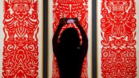 Seorang wanita mengambil foto seni potong kertas tradisional China yang dipamerkan di Museum Seni dan Kerajinan Beijing selama perayaan Tahun Baru Imlek di Beijing, Minggu (29/1/2023). Orang-orang China sedang menikmati liburan selama seminggu untuk Imlek Tahun Baru dan mengunjungi berbagai pameran dan pameran kuil yang diadakan di kota-kota di seluruh China. AP/Andy Wong