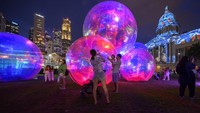 Sebuah keluarga berfoto di Light to Night Festival 2023 Art Skins on Monuments National Gallery di Singapura. AP/Yeen Ling Chong