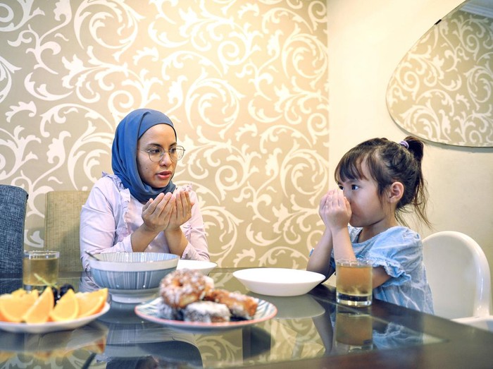 Young asian daughter eating with mother in the kitchen