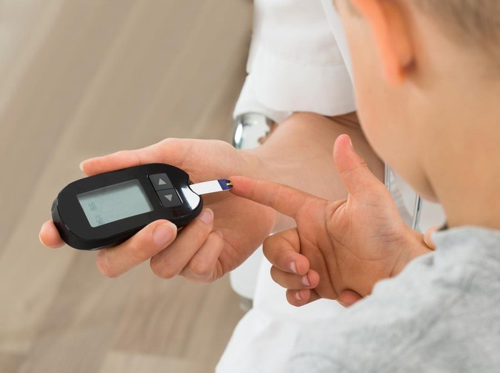 Close-up Of Doctor Measuring Blood Sugar Of Child Patient With Glucometer