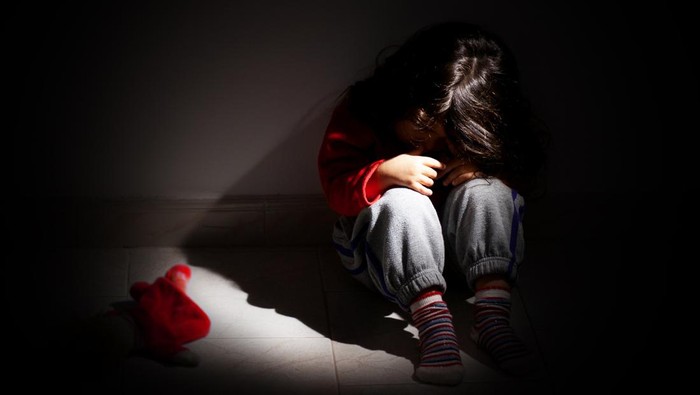 young girl sitting down alone in the dark.