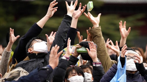 Orang-orang mencoba menangkap kacang keberuntungan yang disebarkan oleh selebriti selama Festival Setsubun di Tokyo, Jepang, Jumat (3/2/2023).  