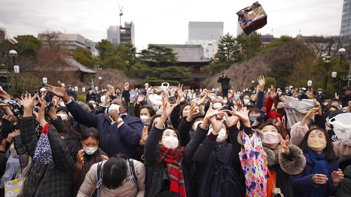 People try to catch lucky beans scattered by celebrities during the 