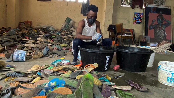 Nigerian artist Eugene Komboye scrolls through his page on instagram where he posts images of artworks he created using discarded plastic flip-flop sandals, in his studio in Abeokuta, Ogun state, Nigeria, January 21, 2023. REUTERS/Seun Sanni