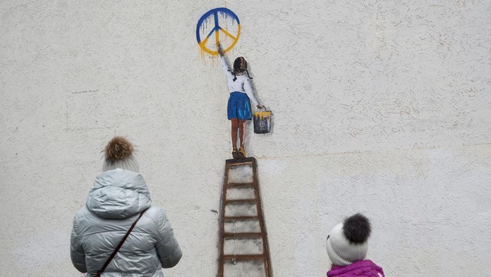Anastasia, 4, stands next to an artwork of the famous street artist Tvboy in the town centre, amid Russia's attack on Ukraine, in Bucha, outside Kyiv, Ukraine January 29, 2023. REUTERS/Valentyn Ogirenko     TPX IMAGES OF THE DAY