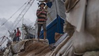Seorang pekerja melintasi tanggul semi permanen yang rusak di Pelabuhan Sunda Kelapa, Jakarta, Kamis (2/2/2023).
