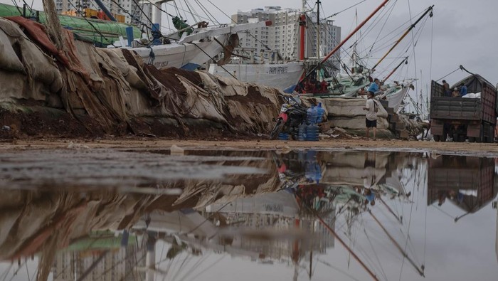 Sejumlah pekerja menaikkan barang ke kapal di dekat tanggul semi permanen kawasan Pelabuhan Sunda Kelapa, Jakarta, Kamis (2/2/2023). Tanggul sementara dari tanah setinggi dua meter di sepanjang dermaga yang berfungsi sebagai penahan banjir rob tersebut telah rusak.  ANTARA FOTO/Wahyu Putro A/foc.