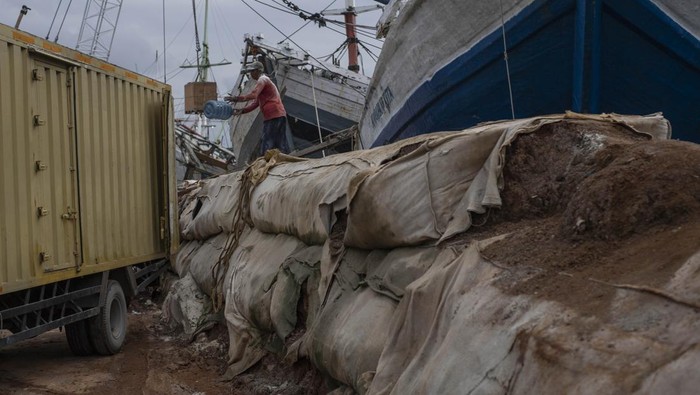 Sejumlah pekerja menaikkan barang ke kapal di dekat tanggul semi permanen kawasan Pelabuhan Sunda Kelapa, Jakarta, Kamis (2/2/2023). Tanggul sementara dari tanah setinggi dua meter di sepanjang dermaga yang berfungsi sebagai penahan banjir rob tersebut telah rusak.  ANTARA FOTO/Wahyu Putro A/foc.