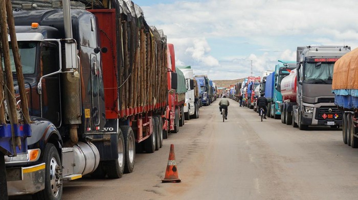 Ratusan Truk Terlantar Berhari-hari di Perbatasan Peru-Bolivia Truck drivers eat by their vehicles which remain lined up for days waiting for the road to Bolivia to open at the Desaguadero border pass in Peru on February 2, 2023. - More than 300 lorries are parked in parallel lines waiting for the end of the strike called by opposers to Peruvian President Dina Boluarte. The strike, effective in several regions of Peru, has affected the distribution and caused shortages of fuel, gas, water and food in several cities in the southeast of the country. (Photo by Bernat BIDEGAIN / AFP) (Photo by BERNAT BIDEGAIN/AFP via Getty Images)