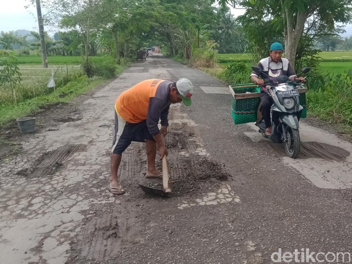 Warga menambal lubang di jalan Wedi-Bayat Klaten dengan tanah, Jumat (3/2/2023).