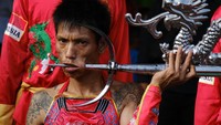 Seorang Tatung menancapkan besi tajam yang cukup besar ke dalam mulutnya lewat pipi. 