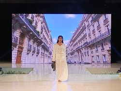 Model Ari Banerjee mengenakan rancangan bertema sederhana buatan Resort Wear dari Uluwatu Lace berwarna putih dengan tas hitam mungil.