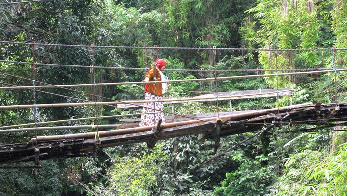 Seorang warga meniti jembatan gantung yang rusak di Desa Halunuk, Kabupaten Hulu Sungai Selatan, Kalimantan Selatan, Minggu (5/2/2023). Menurut warga setempat, jembatan gantung yang merupakan akses utama penghubung antardesa itu kondisinya telah rusak sejak tujuh tahun silam dan membahayakan bagi yang melintas, ANTARA FOTO/Bayu Pratama S/tom.