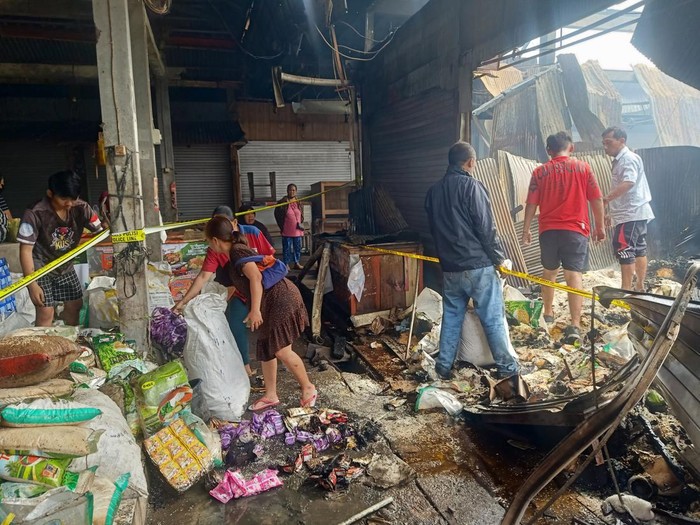 Para pedagang di Pasar Adat Lelateng memindahkan sisa barang dagangan yang tidak terbakar, Minggu (5/2/2023). (Foto: I Putu Adi Budiastrawan/detikBali)