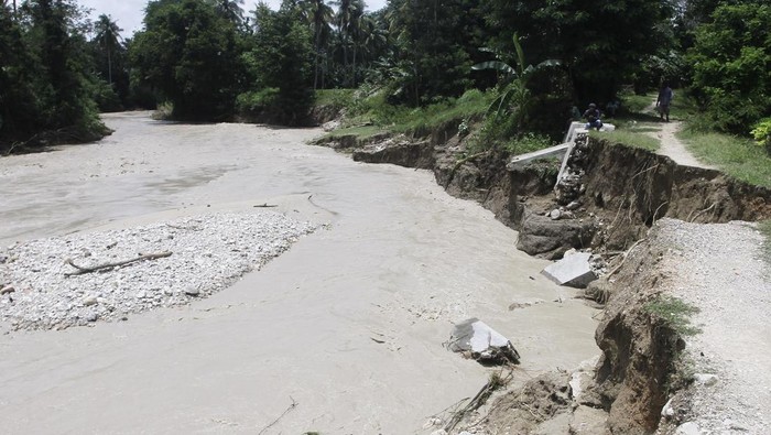 Sejumlah warga duduk di pinggiran sungai menyaksikan derasnya aliran air akibat jebolnya pintu air Bendungan Oesao di Desa Pukdale, Kabupaten Kupang, NTT, Minggu (5/2/2023). Jebolnya pintu air bendungan tersebut mengakibatkan 598 rumah terendam banjir dan dikhawatirkan berdampak pada gagal panen di daerah itu. ANTARA FOTO/Kornelis Kaha/tom.