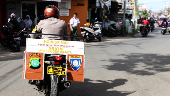 Polisi Aipda Mohadi berkeliling menggunakan kendaraan untuk berbincang dengan warga sambil memberikan kopi gratis di Cilodong, Depok, Jawa Barat, Senin (6/2/2023). Anggota Bhabinkamtibmas Polsek Sukmajaya tersebut secara swadaya membuat program NGUCUR MAS (Ngopi curhat bersama Binmas) dengan memberikan kopi gratis sambil berbincang dengan warga untuk memberikan rasa kenyamanan dan keamanan di wilayahnya. ANTARA FOTO/Asprilla Dwi Adha/nym.