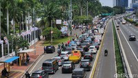 Kendaraan pribadi yang ditumpangi pendemo terparkir paralel sehingga satu lajur menyempit.