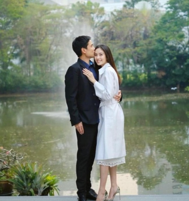 Di Instagramnya, Nong Poy membagikan foto bersama calon suaminya itu. Bergaya formal dengan trench coat putih, ia bersanding dengan Oak yang memakai jas. Nong Poy memamerkan cincin tunangannya.Foto: Dok. Instagram