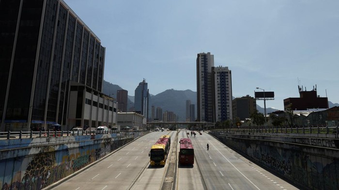 Transmilenio buses run on an avenue during 