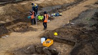 Pekerja penggalian dari Kantor Negara Bagian Saxony-Anhalt untuk Pelestarian Monumen dan Arkeologi menutupi lubang berisi fosil tulang sapi untuk melindungi situs penggalian dari cuaca.