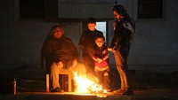 Mereka harus bertahan di tengah udara dingin. Beberapa dari mereka bahkan menyalakan api unggun untuk menghangatkan diri. (Mustafa Bathis/Anadolu Agency via Getty Images)  