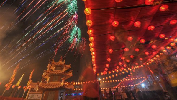 Sejumlah warga menyaksikan pesta kembang api saat puncak perayaan Cap Go Meh di Kelenteng Leng Chun Keng, Jambi, Minggu (5/2/2023). Puncak perayaan Cap Go Meh di daerah itu dimeriahkan dengan beberapa kegiatan hiburan dan pesta kembang api. ANTARA FOTO/Wahdi Septiawan.
