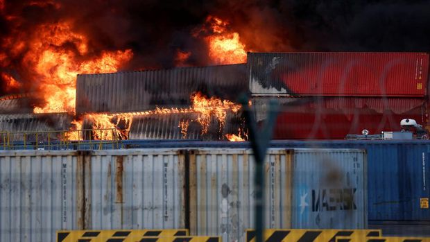 Asap mengepul dari kontainer yang terbakar di sebuah pelabuhan di kota Iskenderun yang dilanda gempa, Turki, 7 Februari 2023. (REUTERS/Benoit Tessier)
