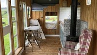 Trailer dengan lebar 7 kaki dan panjang 21 kaki ini berisi dua tempat tidur double, dapur, kompor kayu bakar, dan area tempat duduk dalam ruangan.