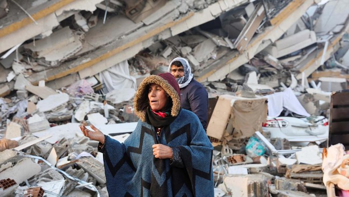 People sit amid rubble following an earthquake in Hatay, Turkey, February 7, 2023. REUTERS/Umit Bektas
