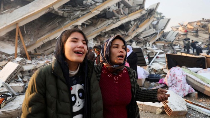 Isak Tangis Korban Gempa di Hatay Turki People sit amid rubble following an earthquake in Hatay, Turkey, February 7, 2023. REUTERS/Umit Bektas