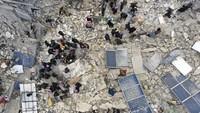 Pekerja pertahanan sipil dan penduduk mencari korban gempa di antara puing-puing bangunan yang runtuh di kota Harem dekat perbatasan Turki, provinsi Idlib, Suriah, Senin (6/2/2023).