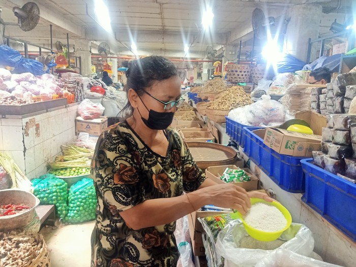 Salah satu pedagang di Pasar Badung, ketika tengah menunjukkan stok beras yang dimilikinya, Selasa (7/2/2023). (Ni Made Lastri Karsiani Putri-detikBali)