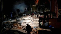Tidak hanya siang, pencarian korban gempa juga dilakujan saat malam hari. Berbekal penerangan ekskavator, tim SAR menyisir reruntuhan bangunan. Reuters/Dilara Senkaya.