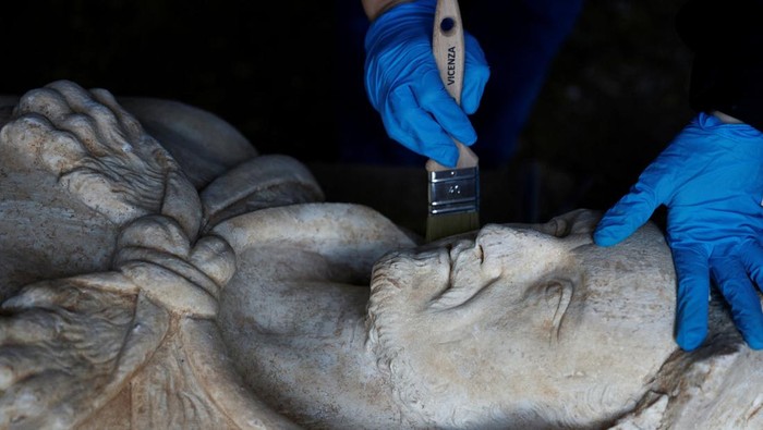 Wujud Patung Romawi Mirip Hercules yang Ditemukan di Selokan Kota Roma Restorer from Appia Antica archaeological park Sara Iovine cleans a life-sized statue of a Roman emperor posing as the classical hero Hercules after it was discovered during sewer repair works near the old Appian Way, ancient Rome's first highway, in Rome, Italy, February 1, 2023. REUTERS/Guglielmo Mangiapane