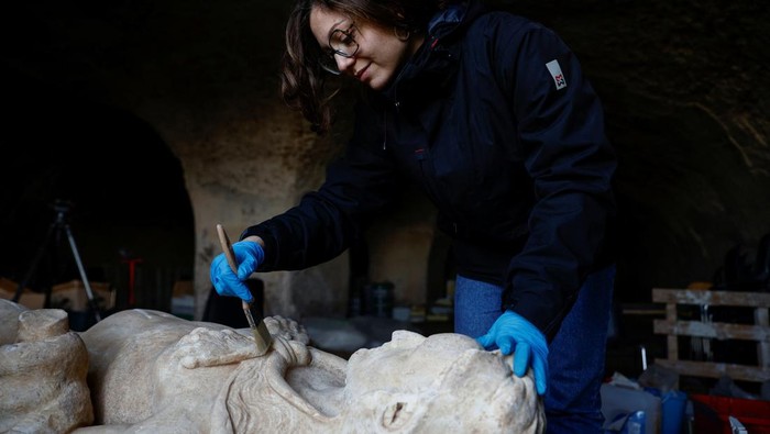 Wujud Patung Romawi Mirip Hercules yang Ditemukan di Selokan Kota Roma Restorer from Appia Antica archaeological park Sara Iovine cleans a life-sized statue of a Roman emperor posing as the classical hero Hercules after it was discovered during sewer repair works near the old Appian Way, ancient Rome's first highway, in Rome, Italy, February 1, 2023. REUTERS/Guglielmo Mangiapane