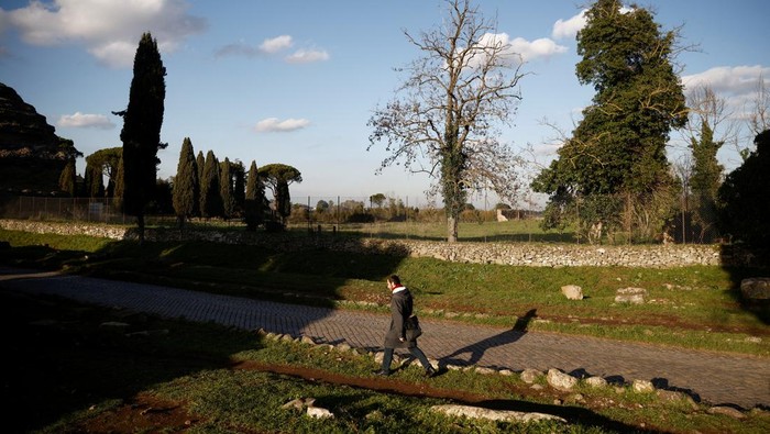 Wujud Patung Romawi Mirip Hercules yang Ditemukan di Selokan Kota Roma A man walks on the old Appian Way, ancient Rome's first highway, near the area where a life-sized statue of a Roman emperor posing as the classical hero Hercules was discovered during sewer repair works in Rome, Italy, February 1, 2023. REUTERS/Guglielmo Mangiapane