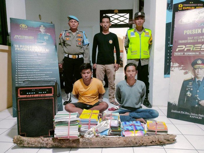 Dua pelaku pencuri buku-buku pelajaran di TK PKK Pandean, Paiton, Probolinggo beserta barang buktinya.