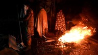 Orang-orang beristirahat di samping api unggun di reruntuhan di Kahramanmaras, Turki. Ozan Kose/AFP/Getty Images  
