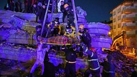 Sejumlah petugas penyelamat mengevakuasi sebuah keluarga dari puing-puing bangunan yang runtuh di Gaziantep, Turki, Selasa (7/2/2023).  