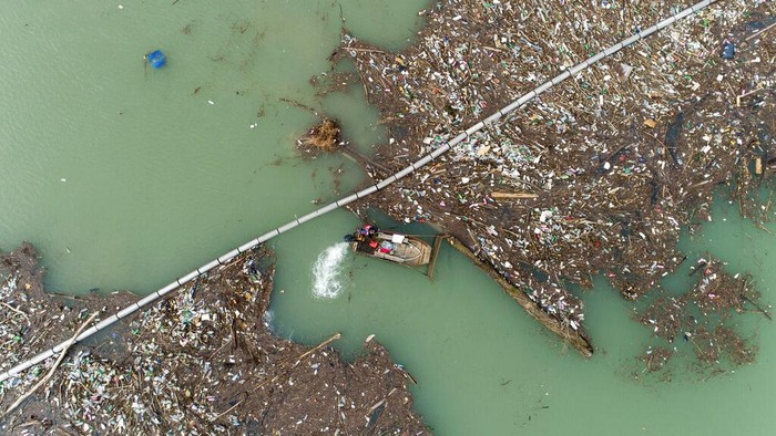 Utility company workers push the waste to the shore of Lim river near Priboj, Serbia, Monday, Jan. 30, 2023. Plastic bottles, wooden planks, rusty barrels and other garbage dumped in poorly regulated riverside landfills or directly into the rivers accumulated during high water season, behind a trash barrier in the Lim river in southwestern Serbia. (AP Photo/Armin Durgut)
