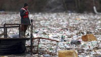 Pekerja perusahaan utilitas mendorong limbah ke tepi sungai Lim dekat Priboj, Serbia, Senin (30/1/2023). Botol plastik, papan kayu, tong berkarat, dan sampah lainnya dibuang di tempat pembuangan sampah tepi sungai yang tidak diatur dengan baik atau langsung ke sungai yang terakumulasi selama aliran tinggi.
