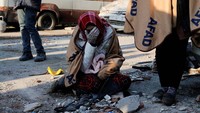 Seorang warga tak kuasa menahan air matanya di sekitar bangunan yang ambuk di Kahramanmaras, Turki. Reuters/Dilara Senkaya.