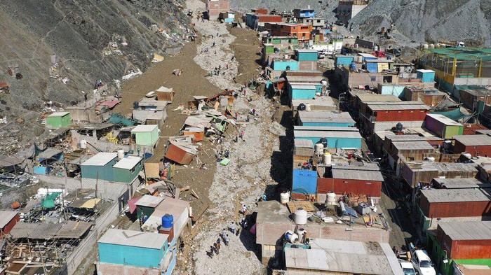 Rumah-rumah di Peru Hancur Tertimbun Longsor, 15 Orang Tewas Residents walk on a street covered with debris caused by a landslide, in Camana, Peru, Tuesday, Feb. 7, 2023. Authorities in Peru say landslides triggered by steady rains swept mud, water and rocks into several villages in the country's southern region. (AP Photo/Jose Sotomayor)